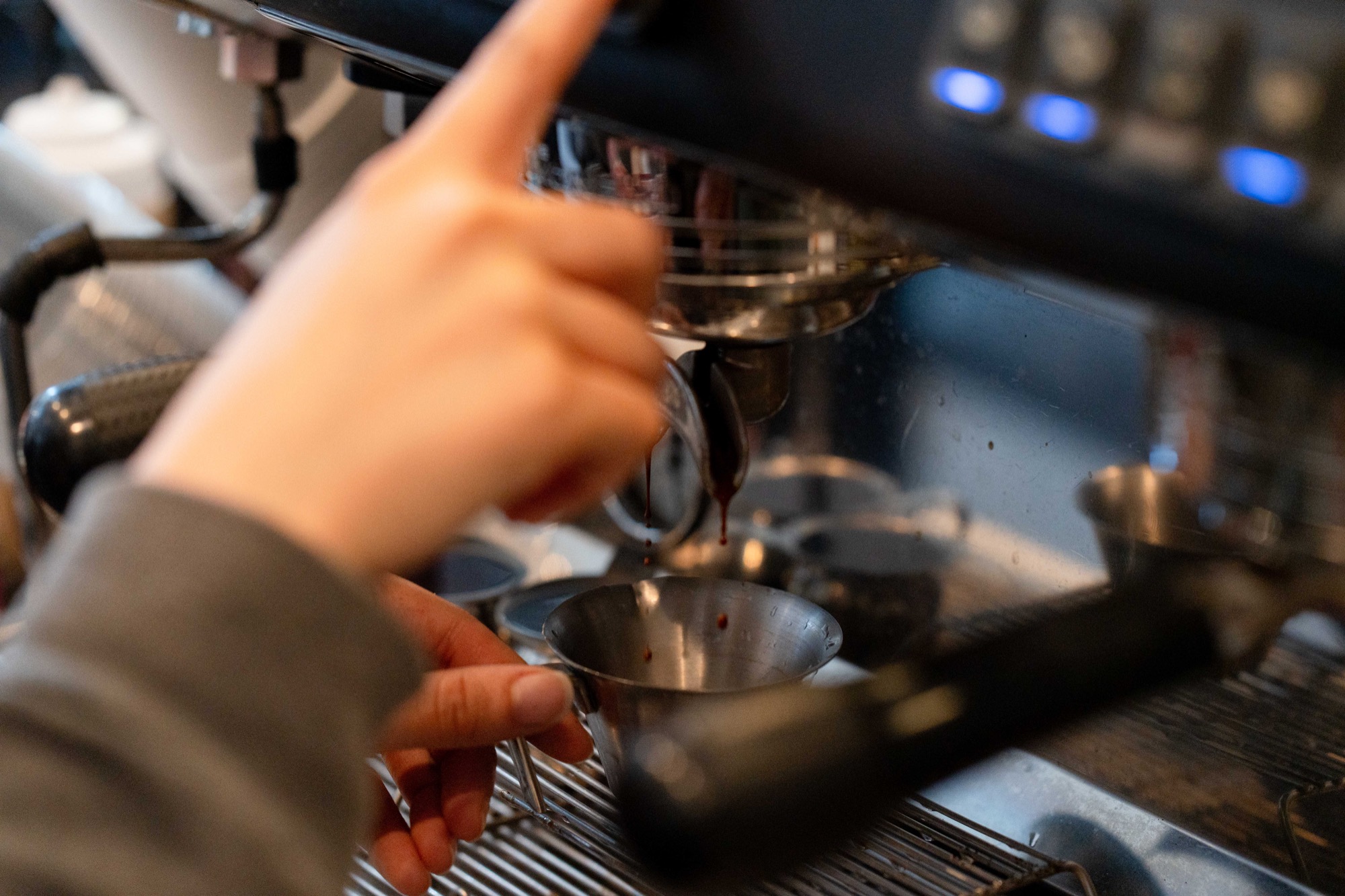 Fresh espresso streaming into a metal shot pitcher