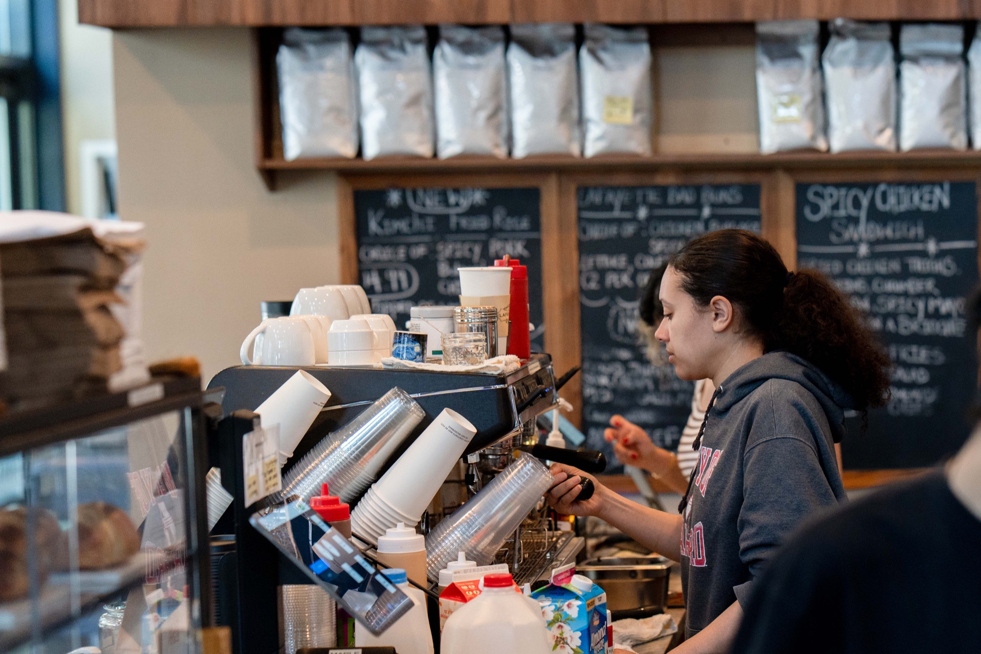 Barista pulling shots at the espresso bar with chalkboard menus behind